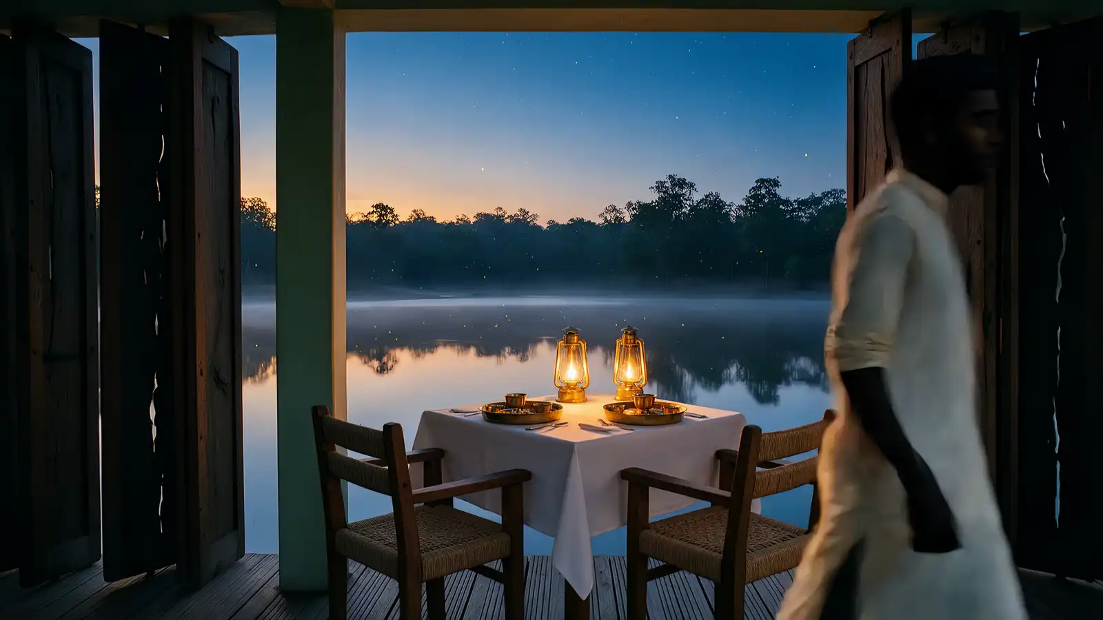At dusk a server lights two lanterns on a table set on the deck above the lake